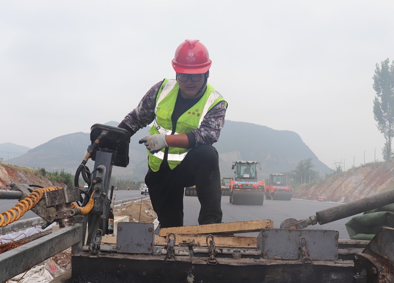 4、油層施工隊長朱紹濤根據(jù)現(xiàn)場實際微調(diào)攤鋪機控制攤鋪質(zhì)量_副本